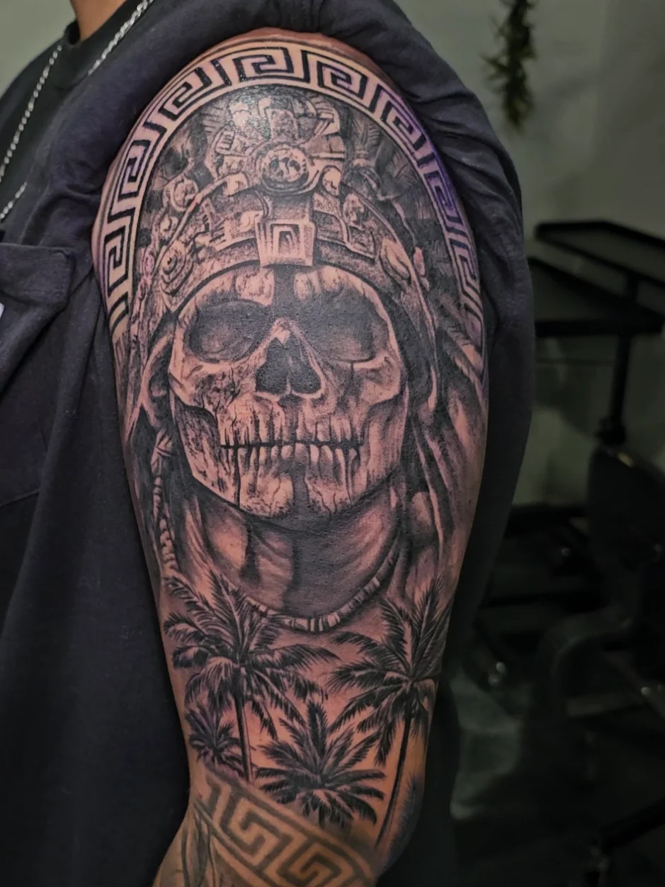 Aztec skull with headdress and geometric borders tattoo by Alex Zamora